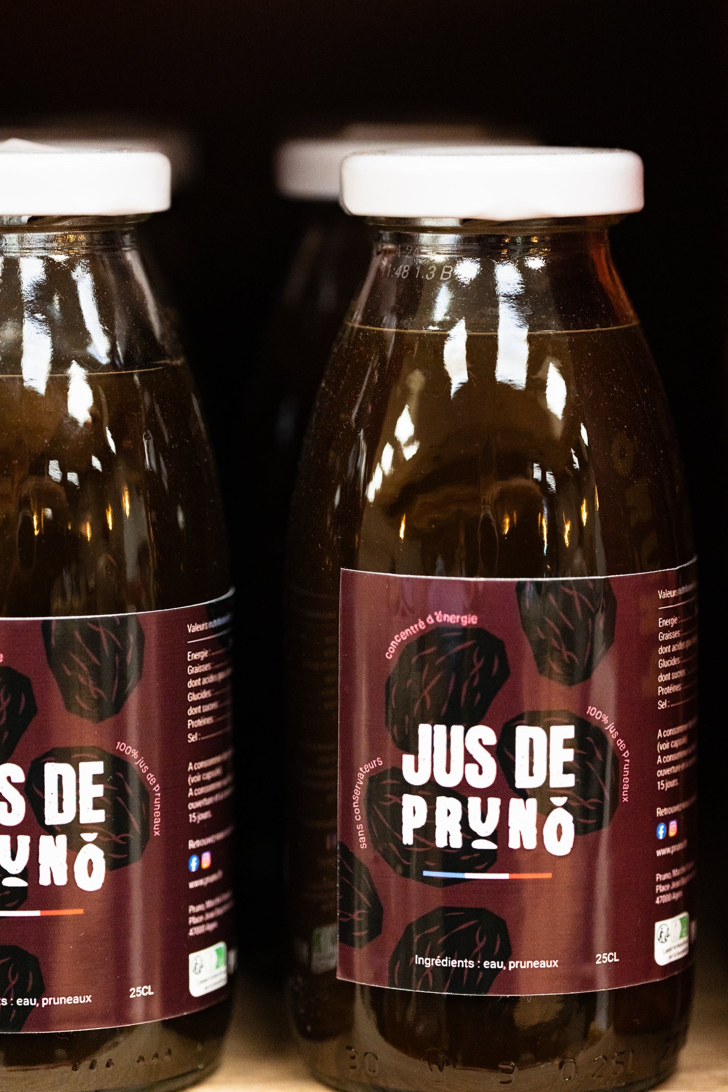 bouteille de jus de pruneaux en verre sur fond neutre